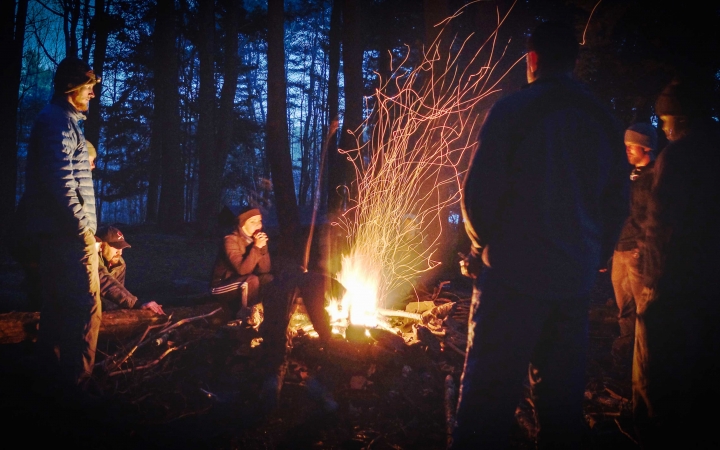 a group of veterans stand around a fire on an outward bound veterans expedition 